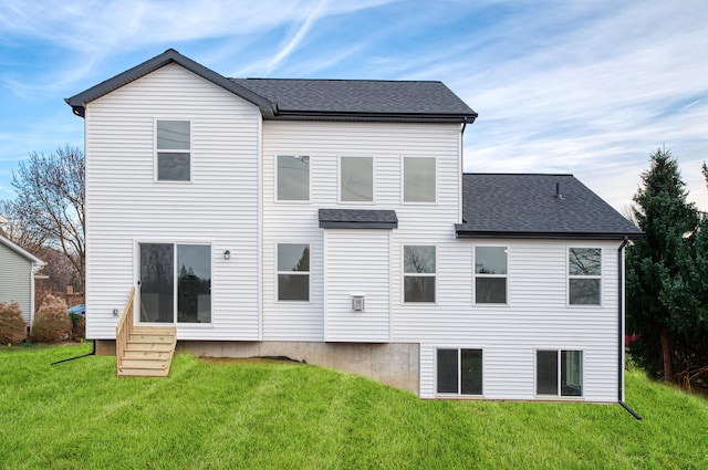 rear view of property featuring entry steps, roof with shingles, and a yard