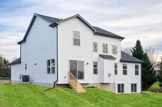 back of property with entry steps, central AC, a lawn, and roof with shingles