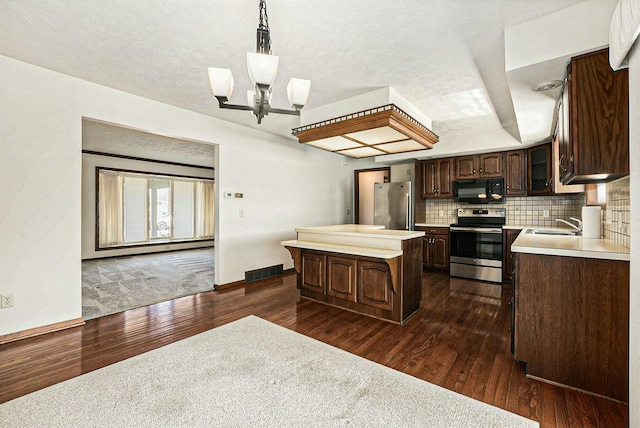 kitchen with visible vents, a kitchen island, dark brown cabinetry, appliances with stainless steel finishes, and tasteful backsplash