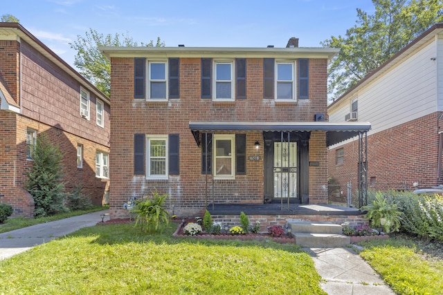 view of front facade featuring covered porch, a front yard, and brick siding