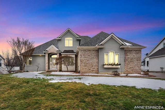 traditional-style home with brick siding, roof with shingles, and a front yard