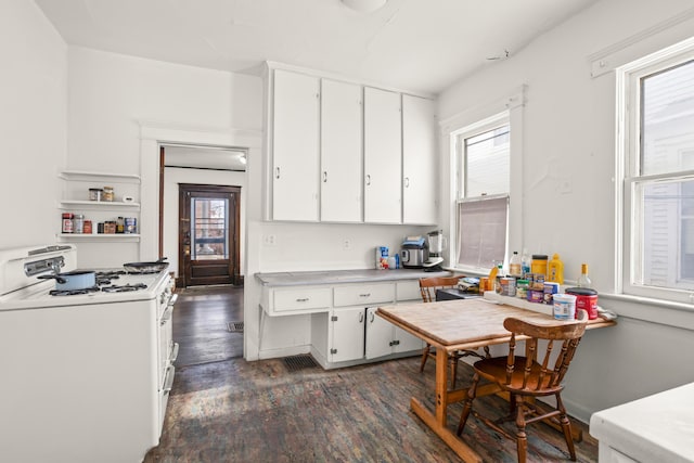 kitchen featuring a healthy amount of sunlight, white gas range, white cabinets, and dark wood-type flooring