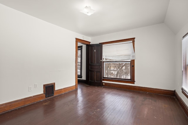 unfurnished room featuring wood-type flooring, visible vents, vaulted ceiling, and baseboards