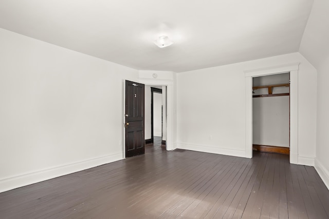 unfurnished bedroom with a closet, dark wood finished floors, and baseboards