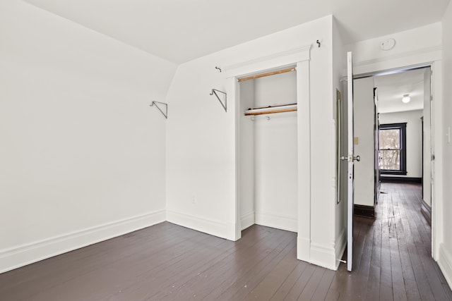 unfurnished bedroom with dark wood-style flooring, a closet, and baseboards