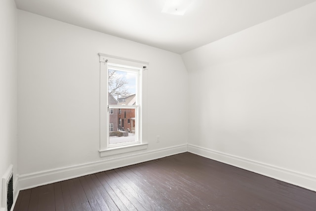 spare room featuring dark wood-style flooring, visible vents, and baseboards