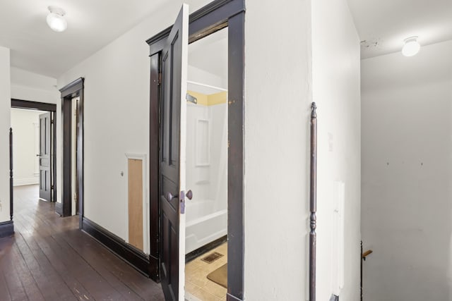 hallway featuring visible vents, baseboards, and hardwood / wood-style flooring