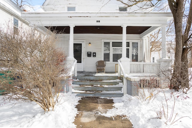 snow covered property entrance featuring covered porch