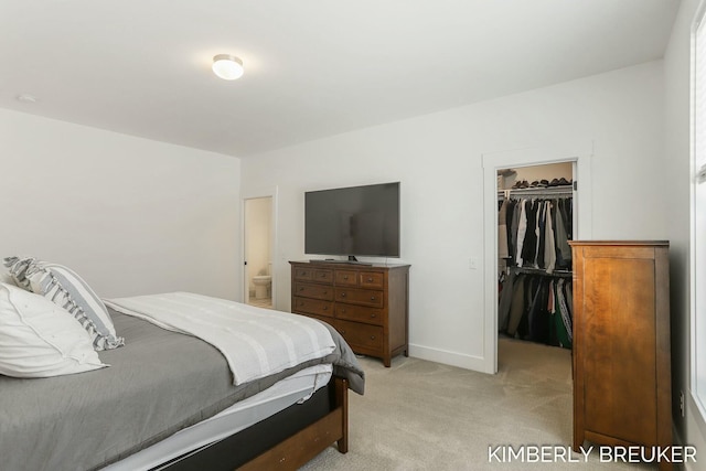 bedroom featuring a closet, a spacious closet, light carpet, connected bathroom, and baseboards