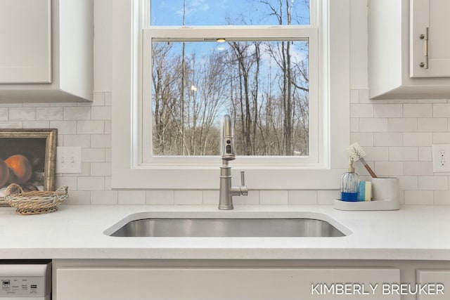 kitchen featuring light countertops, a sink, dishwasher, and white cabinetry