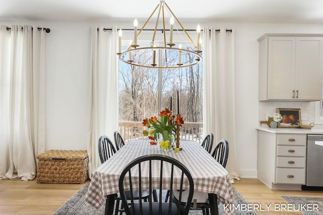 dining area with light wood-style flooring and an inviting chandelier