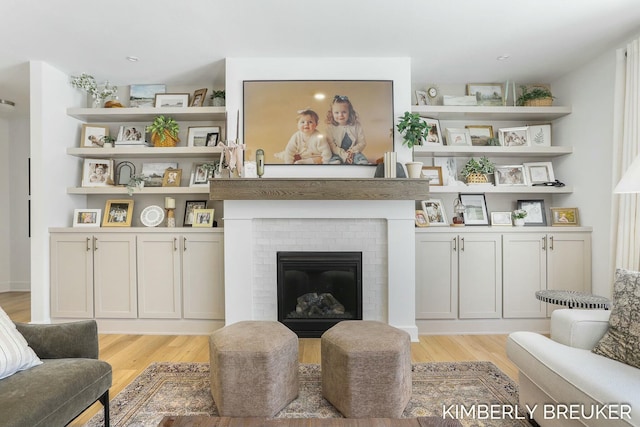 living area featuring light wood finished floors and a brick fireplace