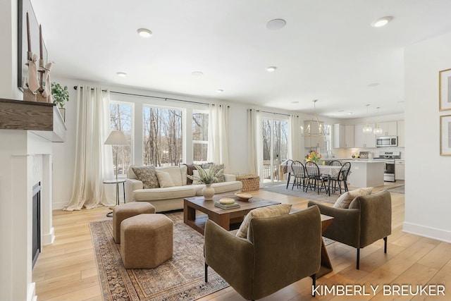 living room featuring light wood finished floors, a wealth of natural light, and a notable chandelier