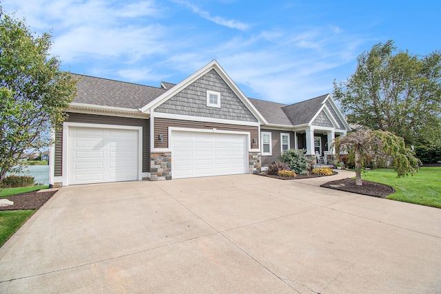 view of front facade featuring driveway, a shingled roof, and a front yard