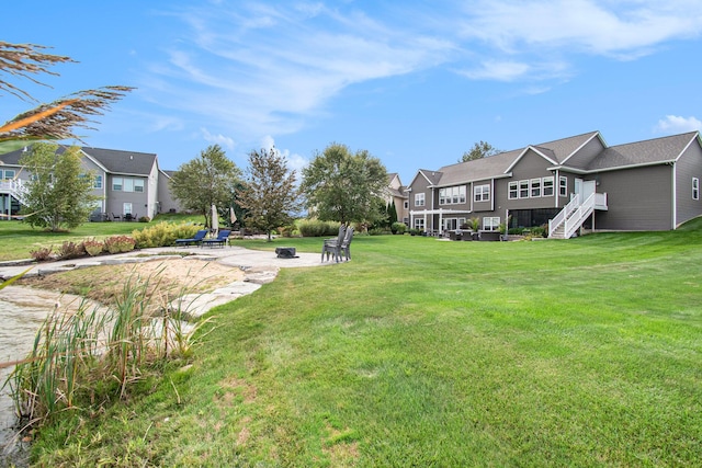 view of yard featuring an outdoor fire pit, a residential view, and stairs