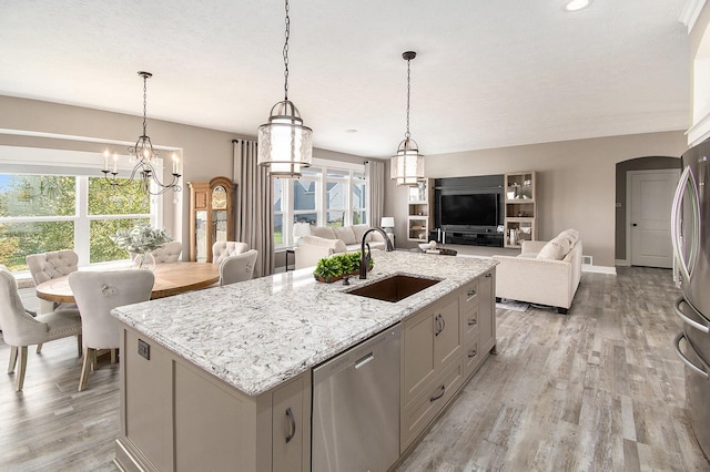 kitchen with a kitchen island with sink, stainless steel appliances, a sink, and open floor plan