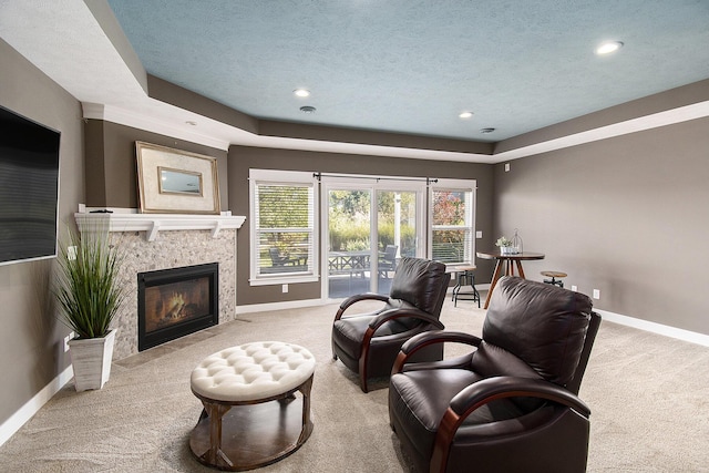 living room with baseboards, a tiled fireplace, and light colored carpet