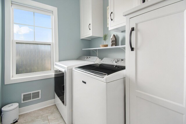 washroom with cabinet space, baseboards, visible vents, and separate washer and dryer