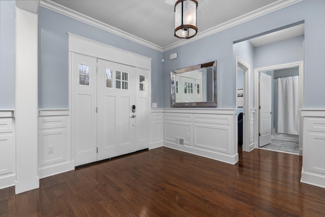 entrance foyer with a wainscoted wall, dark wood finished floors, crown molding, and a decorative wall