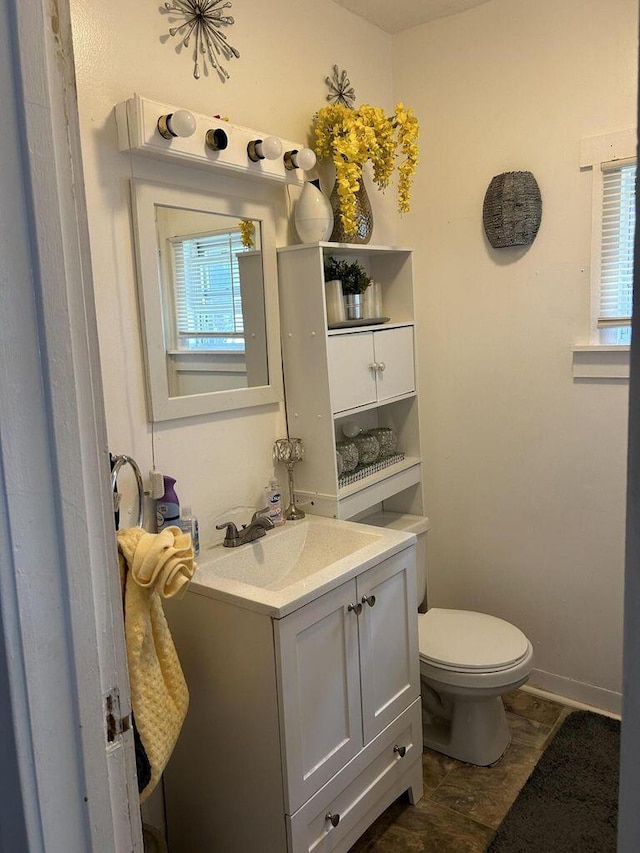 bathroom featuring toilet, vanity, and baseboards