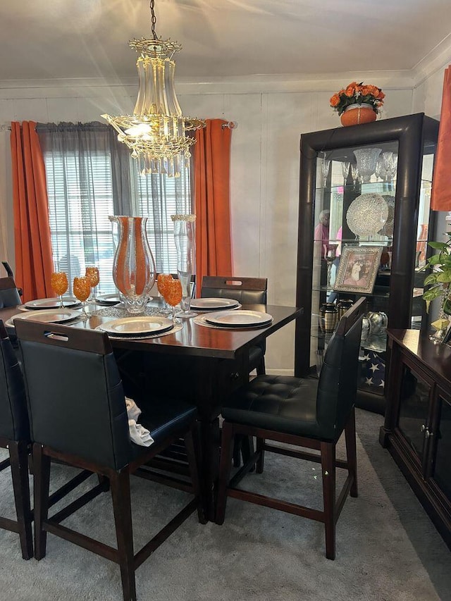 carpeted dining space featuring ornamental molding, a decorative wall, and a notable chandelier