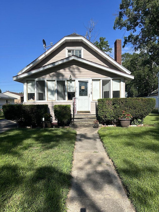 bungalow-style house with entry steps, a front lawn, and a chimney