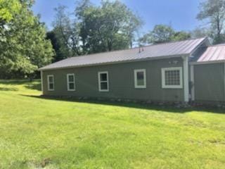 rear view of house with a standing seam roof, metal roof, and a lawn