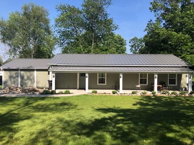 view of front of house featuring metal roof, a porch, and a front yard