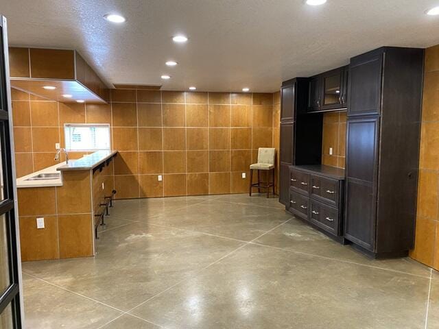 interior space featuring a sink, tile walls, concrete flooring, and recessed lighting