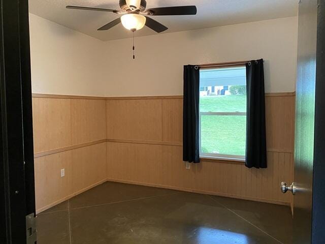 unfurnished room with a healthy amount of sunlight, a wainscoted wall, and concrete floors