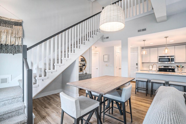 dining room with light wood-style floors, stairs, and visible vents