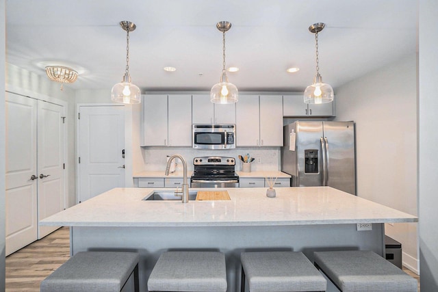 kitchen featuring stainless steel appliances, a sink, hanging light fixtures, and a kitchen bar