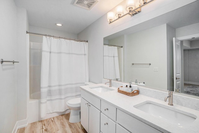 bathroom featuring shower / bathtub combination with curtain, visible vents, a sink, and wood finished floors