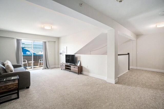 carpeted living room with lofted ceiling and baseboards