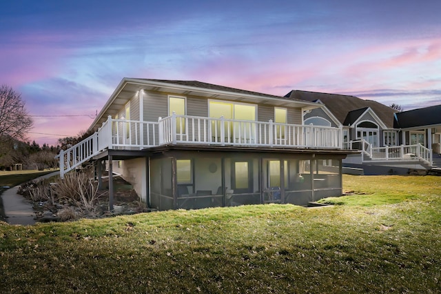 back of house at dusk featuring a lawn