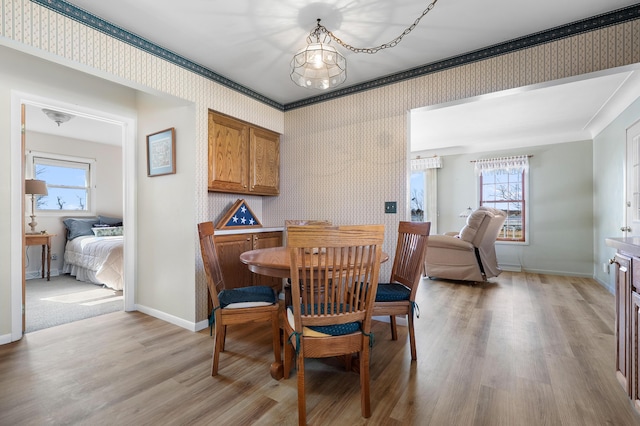 dining room with wallpapered walls, baseboards, and light wood-style floors