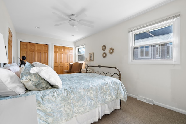 carpeted bedroom with baseboards, visible vents, ceiling fan, and two closets