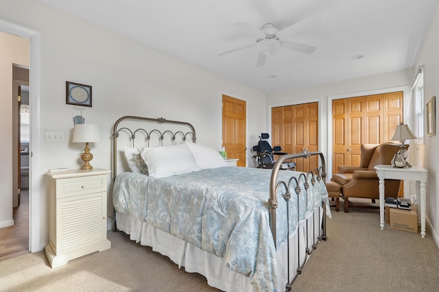 bedroom with carpet floors, two closets, a ceiling fan, and baseboards