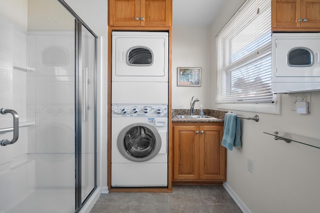 laundry area with light tile patterned floors, laundry area, stacked washer / dryer, a sink, and baseboards