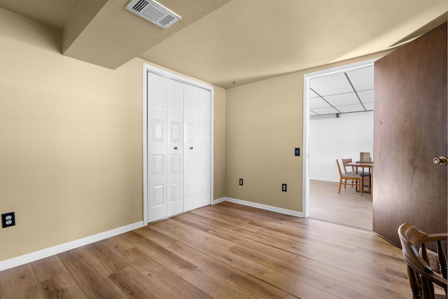 unfurnished bedroom featuring light wood-style flooring, a closet, visible vents, and baseboards