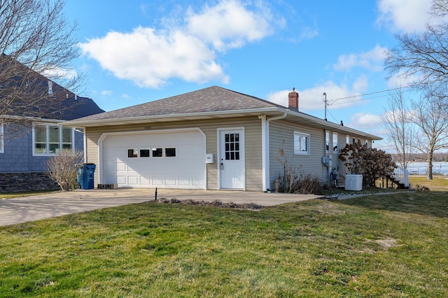exterior space with a yard, concrete driveway, a chimney, and an attached garage