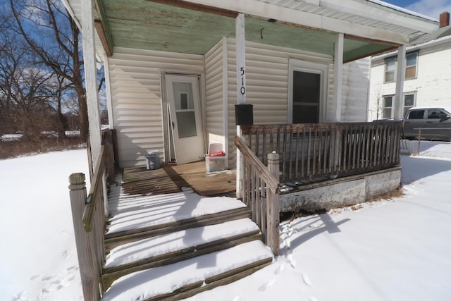 snow covered property entrance with covered porch