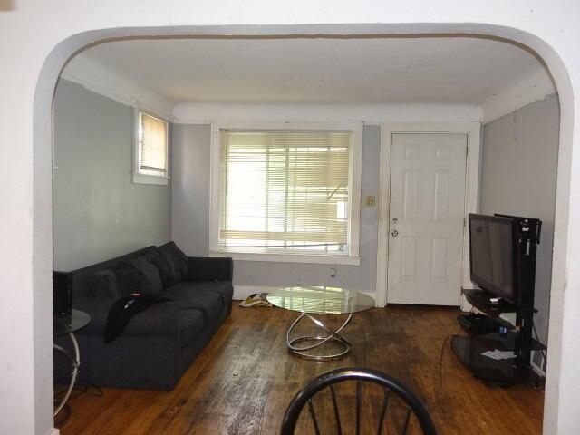 living area with arched walkways and dark wood-style flooring