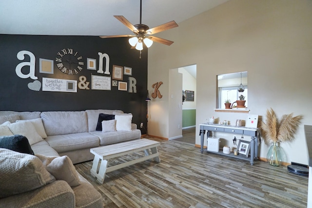 living area with a ceiling fan, a high ceiling, baseboards, and wood finished floors