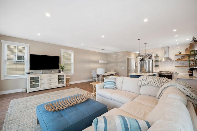 living room featuring light wood-type flooring, baseboards, visible vents, and recessed lighting