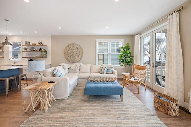 living room with light wood-style floors, recessed lighting, french doors, and baseboards