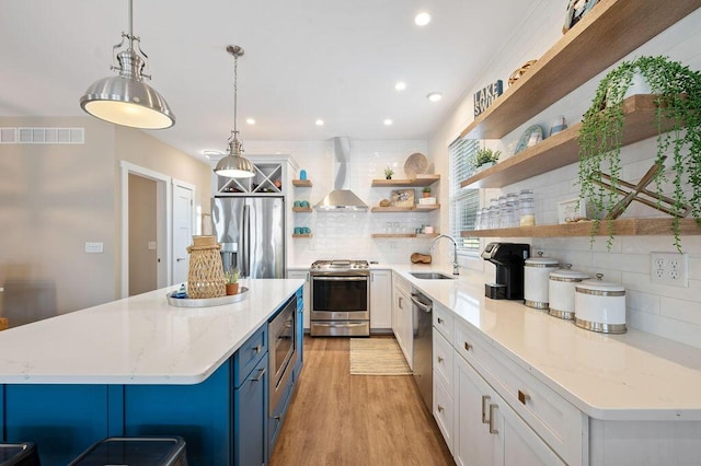 kitchen with appliances with stainless steel finishes, white cabinets, wall chimney range hood, and open shelves