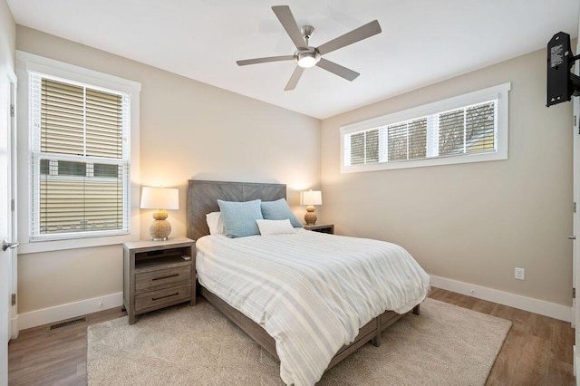 bedroom with light wood-style flooring, visible vents, ceiling fan, and baseboards