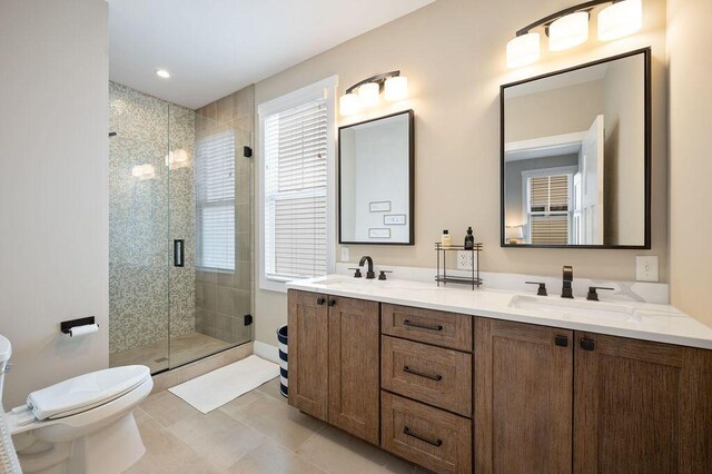 full bath featuring a sink, a shower stall, toilet, and double vanity