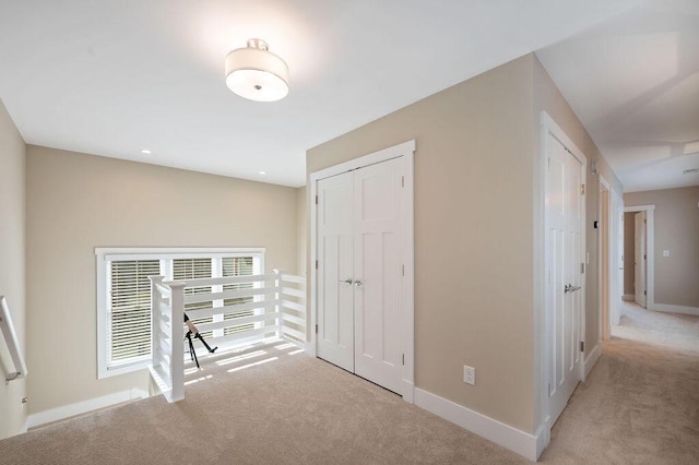 hallway featuring baseboards and light colored carpet